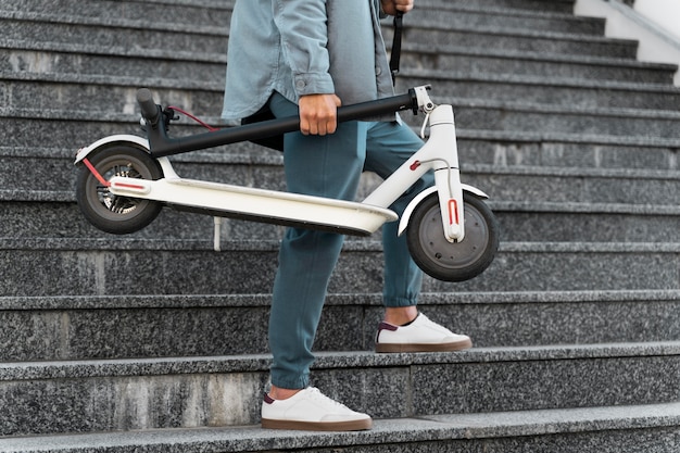 Foto gratuita giovane che si prende una pausa dopo aver guidato il suo scooter all'aperto