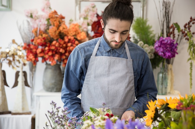 無料写真 フラワーショップで彼の花の花束の世話をする若い男