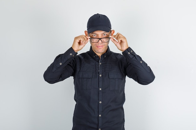 Young man taking off glasses in black shirt