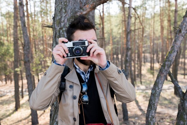 若い男が森の中のカメラで写真を撮影