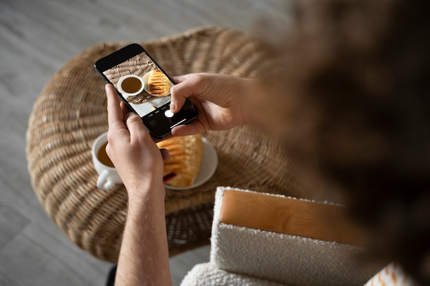 Giovane che scatta una foto della sua colazione usando il suo smartphone