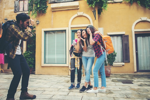 Young man taking selfie of his friends while traveling in urban together.