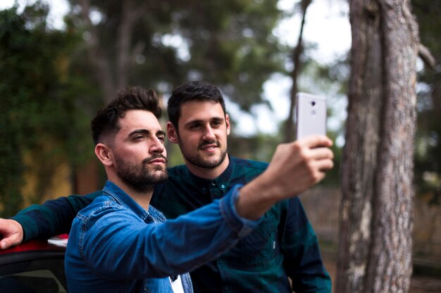 Young man taking selfie on mobile phone with his friend