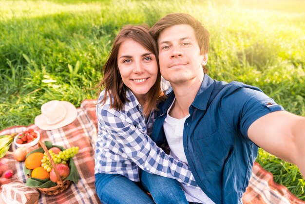 Young man taking selfie with girlfriend on plaid