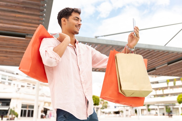Young man taking selfie with shopping bags