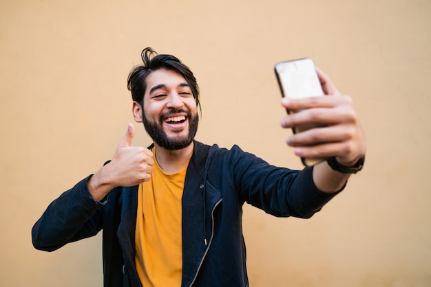 電話でselfiesを取る若い男。