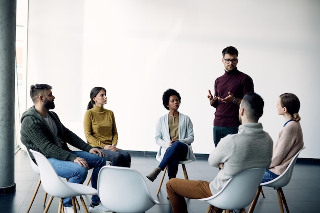 Young man talking about his problems during group psychotherapy