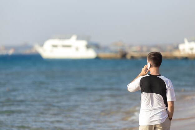 海で携帯電話で話す若い男