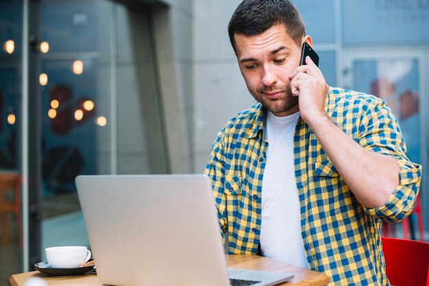 カフェテリアで電話で話す若い男