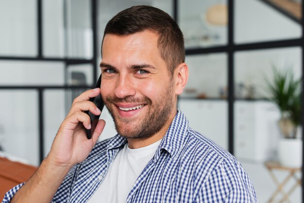 Free photo young man talking at phone while sitting on couch