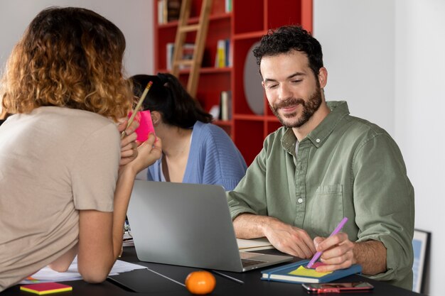 Young man talking with his friends about his notes during study session