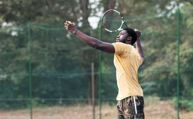 Giovane uomo sul campo da tennis giocando