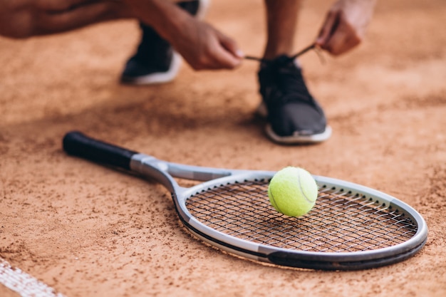 Молодой человек теннисист на корте, теннисная ракетка крупным планом