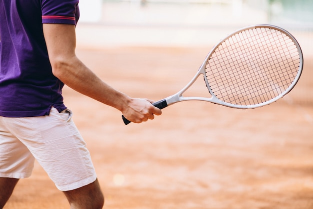 Young man tennis player at the court, tennis racket close up