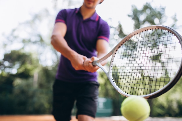 Young man tennis player at the court, tennis racket close up