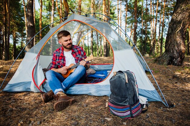 Young man in tent playing quitar