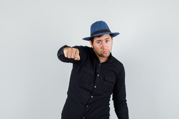 Free photo young man threatening with fist in black shirt