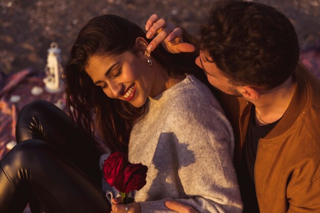 Молодой человек трогательно ухо женщины с розами