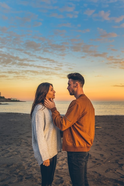 Young man touching woman neck on sea shore 