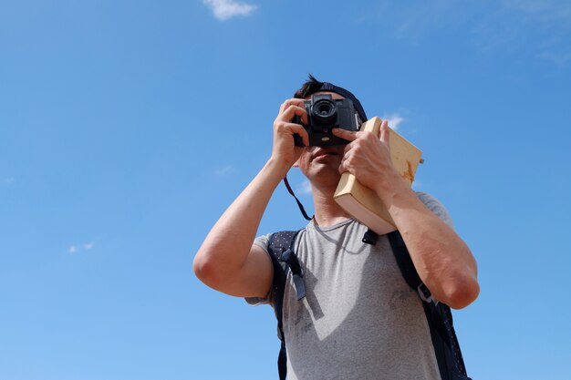 젊은 남자 여행자는 가이드 북, 여행 및 레크리에이션 개념으로 사진을 찍고있다