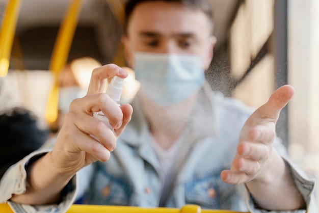 Foto gratuita giovane che viaggia in autobus urbano disinfettando le mani con gel igienizzante