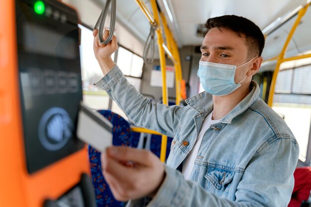 Young man travelling by city bus paying with bus card