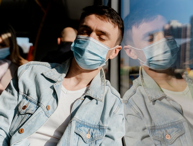 Free photo young man travelling by city bus wearing surgical mask