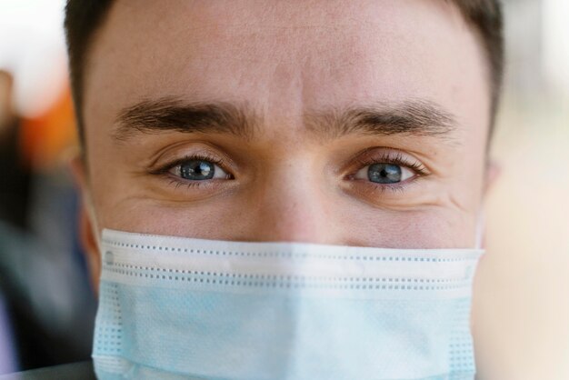 Young man travelling by city bus wearing surgical mask