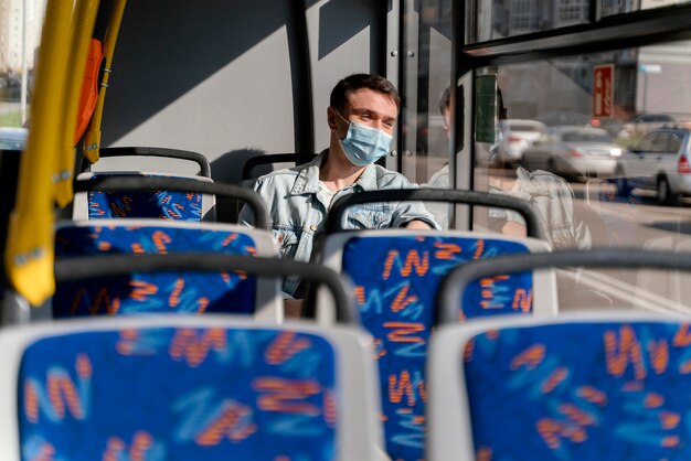 young man travelling by city bus wearing surgical mask