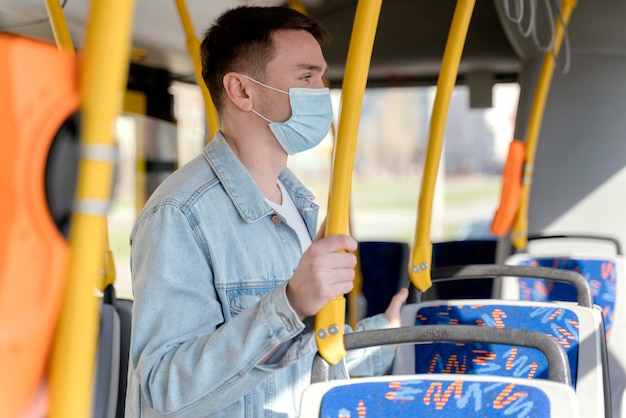수술 용 마스크를 쓰고 시내 버스로 여행하는 젊은 남자