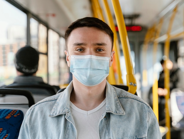 サージカルマスクを身に着けている市バスで旅行している若い男