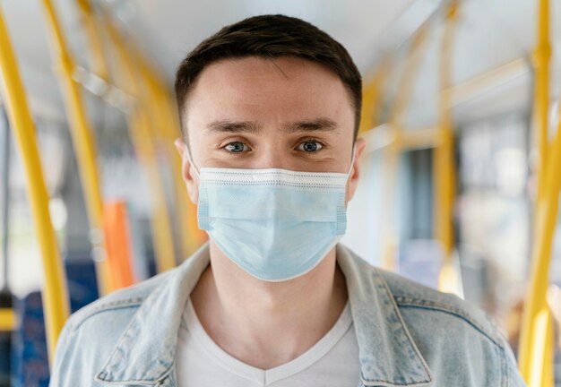 Young man travelling by city bus wearing surgical mask