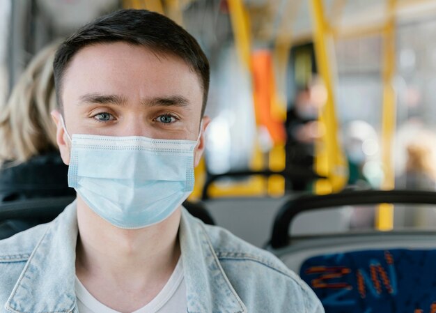 수술 용 마스크를 쓰고 시내 버스로 여행하는 젊은 남자