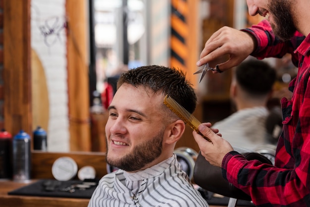 Young man trimming with scissors and comb