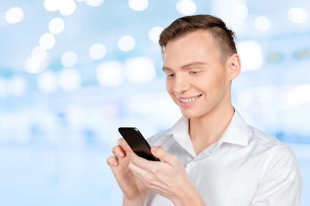 Молодой человек набирает текстовое сообщение на своем мобильном телефоне