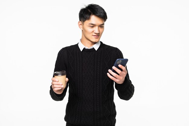 Young man use on mobile phone with coffee on white wall