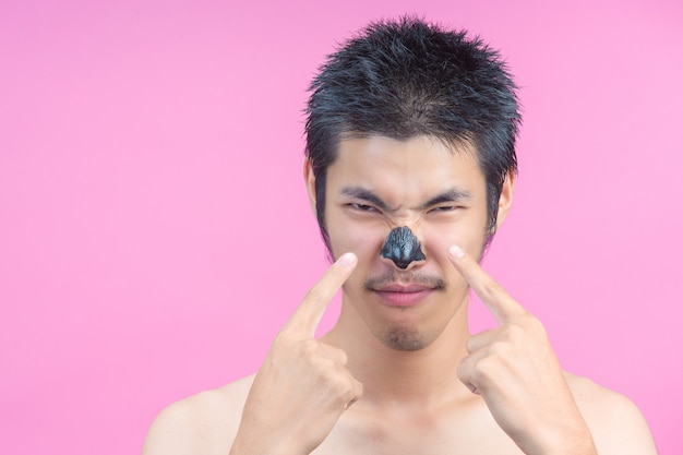 Free photo the young man uses his finger to point at the black cosmetic, on the mucus and the pink .