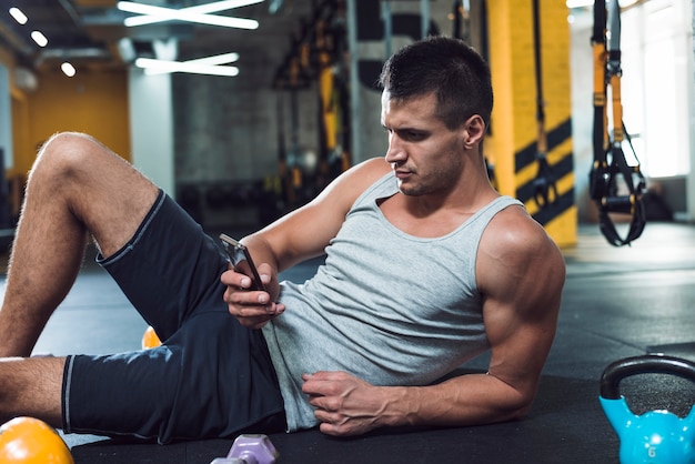 Young man using cellphone in gym