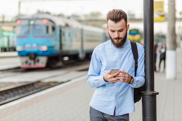 Foto gratuita giovane che per mezzo del cellulare all'aperto