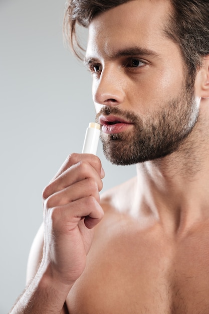 Young man using colorless lipstick