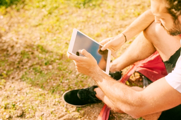 Молодой человек с помощью цифрового планшета на открытом воздухе