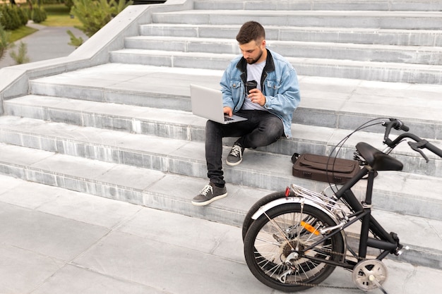 Free photo young man using a folding bike in the city