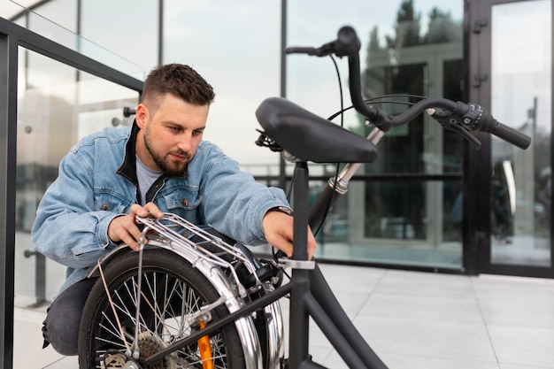 Free photo young man using a folding bike in the city