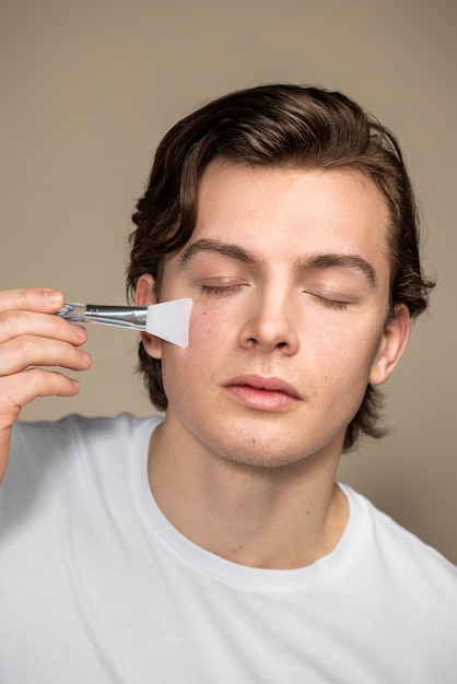 Free photo young man using gua sha tool