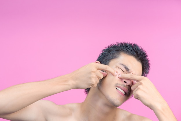 The young man using his hands to squeeze pimples on his face and the pink .