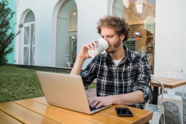 コーヒーショップで彼のラップトップを使用して若い男。