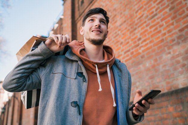 Giovane che per mezzo del suo telefono cellulare sulla via.