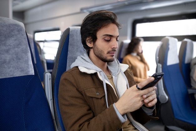 Молодой человек с помощью своего смартфона во время путешествия на поезде