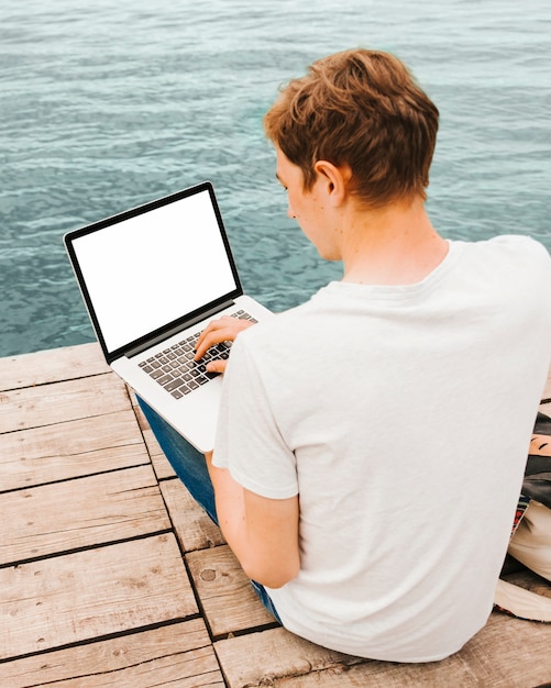 Young man using laptop by the water
