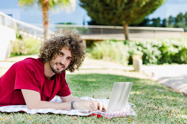 공원 바닥에 노트북을 사용하는 젊은 남자